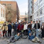 Photo: A large group of young people, likely college students, with bicycles stand on an urban street in Boston University's campus
