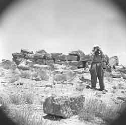 A picture of a man using a camera in the desert.