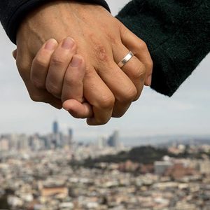 a married couple in san francisco california hold hands with the city in the background
