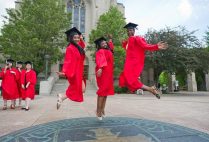 Three Boston University graduating students jump on the BU Seal symbol on Marsh Plaza on Commencement Sunday.
