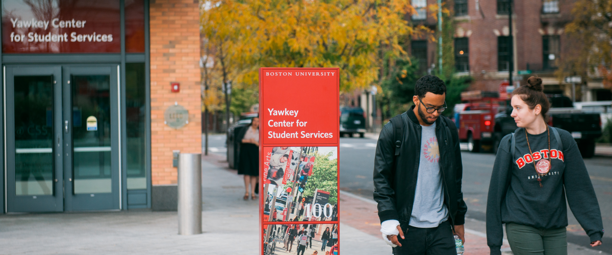 Two students walking by the Yawkey Center for Student Services sign