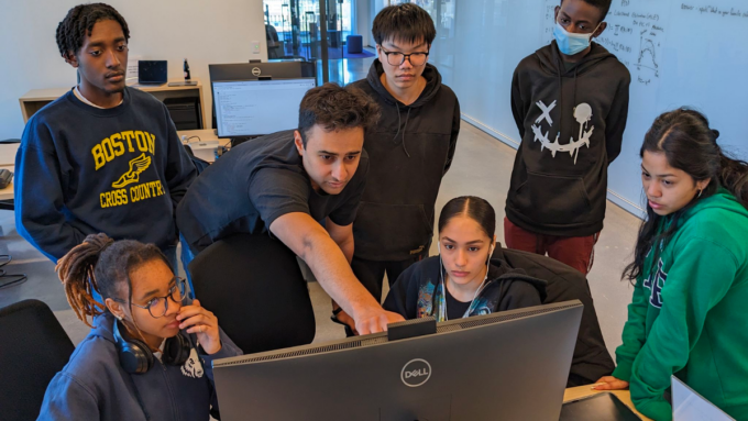 A group of software engineering students gather around a computer.