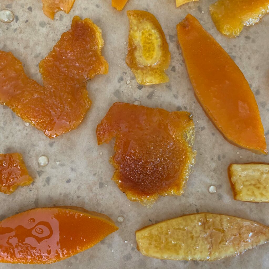 A set of orange peels simmered in simple syrup set out to dry, spaced out so they don't stick.