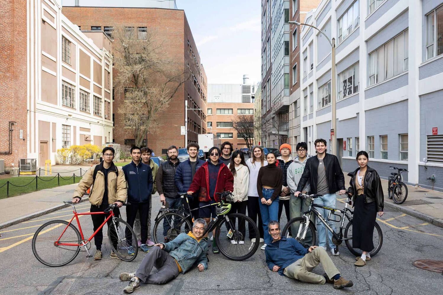 Photo: A large group of young people, likely college students, with bicycles stand on an urban street in Boston University's campus
