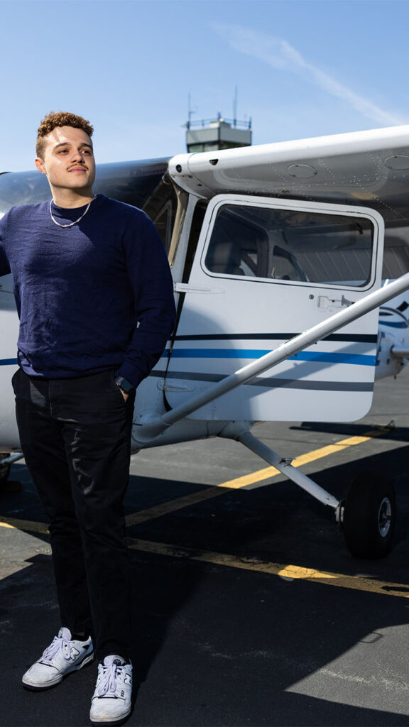 Photo: A young man standing in front of a small Cessna plane