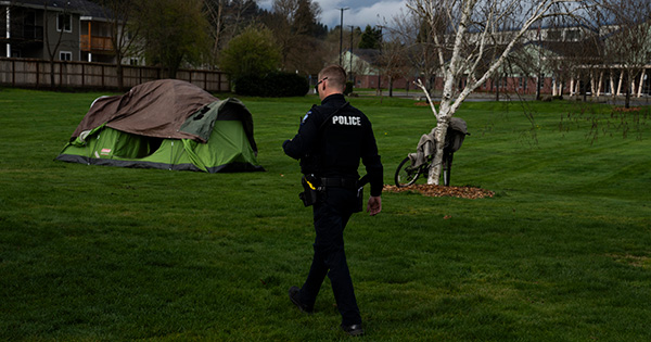 Photo: A picture of a man in a police uniform walking through a field that has a tent.
