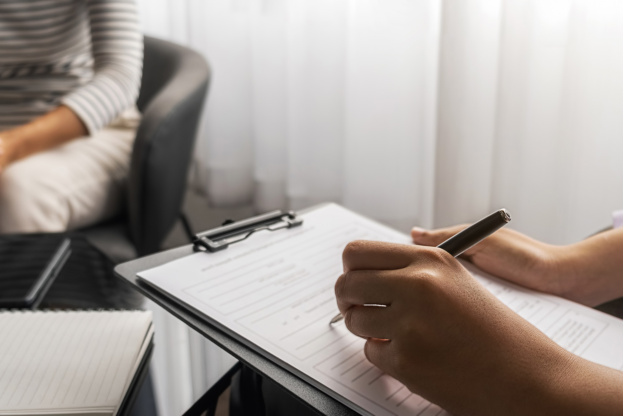 Photo: A therapist filling out an assessment as their patient sits across from them