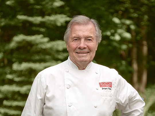 Jacques Pépin poses outdoors in a BU chef jacket