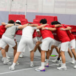 Photo: Members of the BU Mens tennis team put their arms together in a celebratory chant at a recent meet