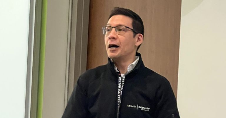 A person lectures from behind a Boston University lectern