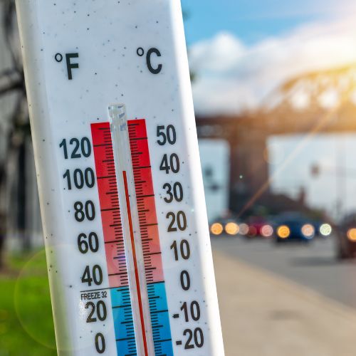 A thermometer with the image of a city in the back.