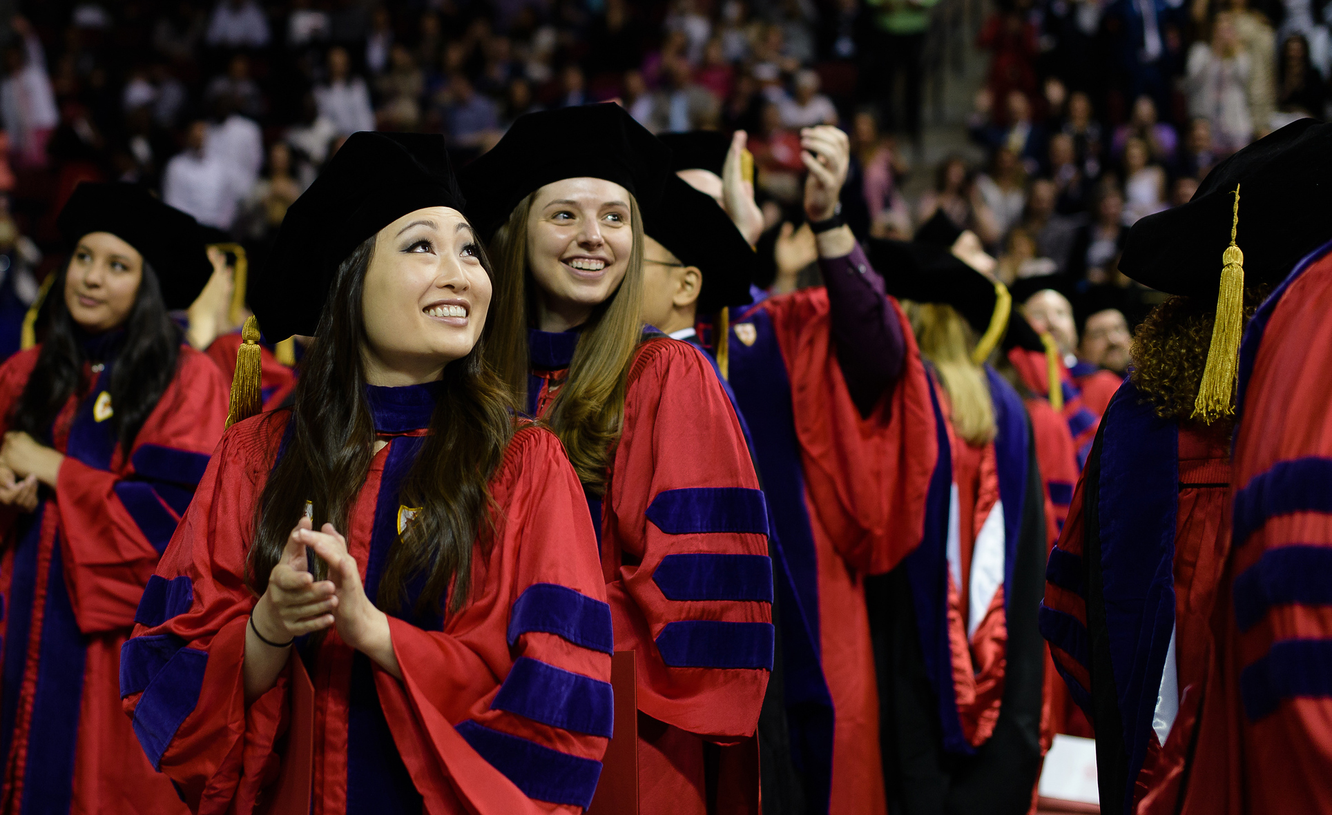 Two smiling BU Law graduates wear red robes at commencement.