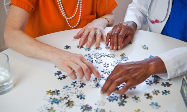 Senior woman and doctor with jigsaw puzzle