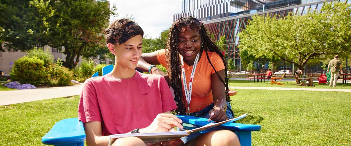 Two BU Summer Term students collaborating on an assignment outdoors, near the Computing & Data Sciences building