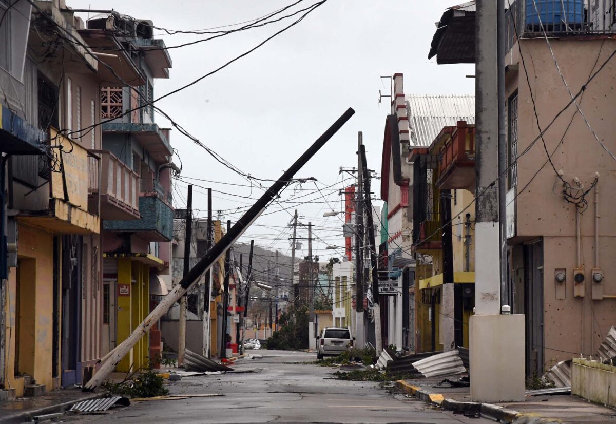 Photo: A picture of a town that has been hit by a hurricane. There is a telephone pole leaning into the street and debris around