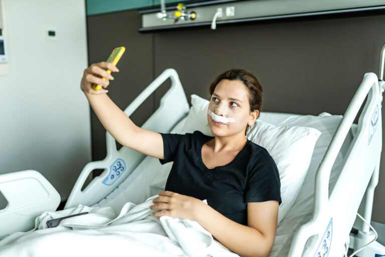 A women looking at her nose reconstruction surgery bandages, through her phone camera