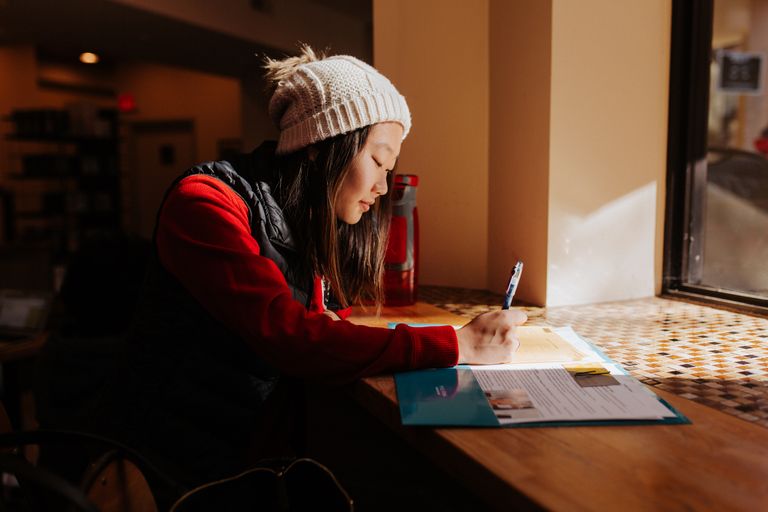 Student writing at a desk