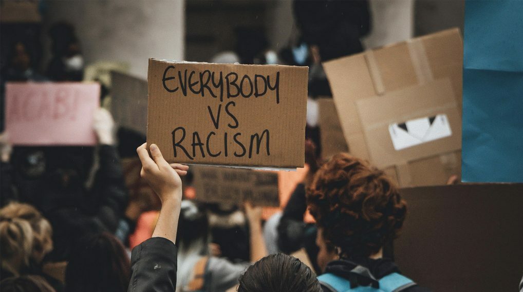 Protester holding Everybody vs. Racism sign