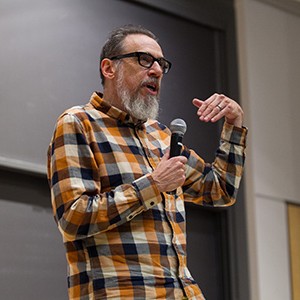 Shot of Larry Charles speaking in front of an auditorium