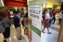 Boston University students file past a "Locally Grown" sign in a BU dining hall. BU Dining Services hit its goal of providing 20% sustainable food three years early.