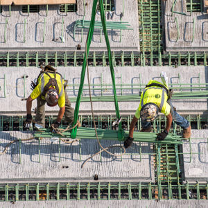 two construction workers balance on a sea of green pegs