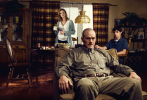 Breaking Bad character Walter White sits in a recliner with his family wife Skylar and son Walt Jr. in the background.