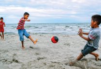 kids playing soccer on the beach