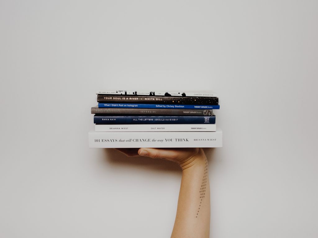 A hand holdng a stack of books