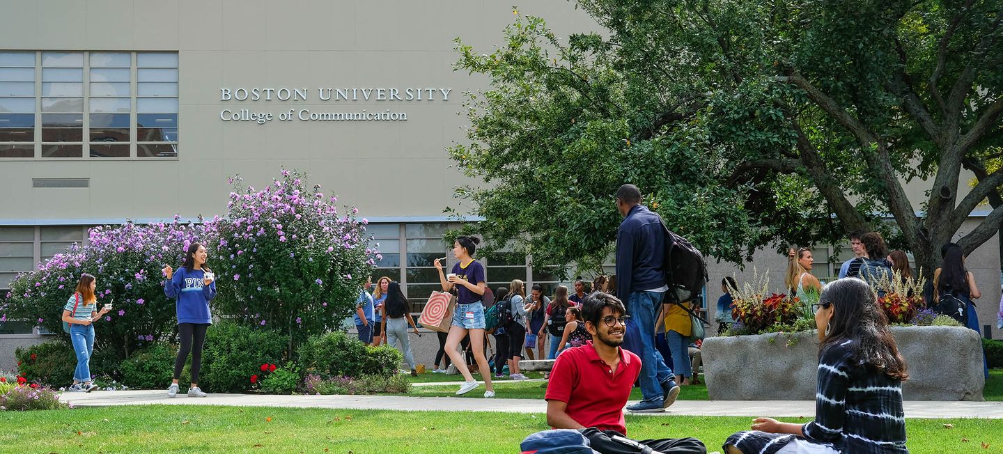 Students chatting while sitting on the COM Lawn.