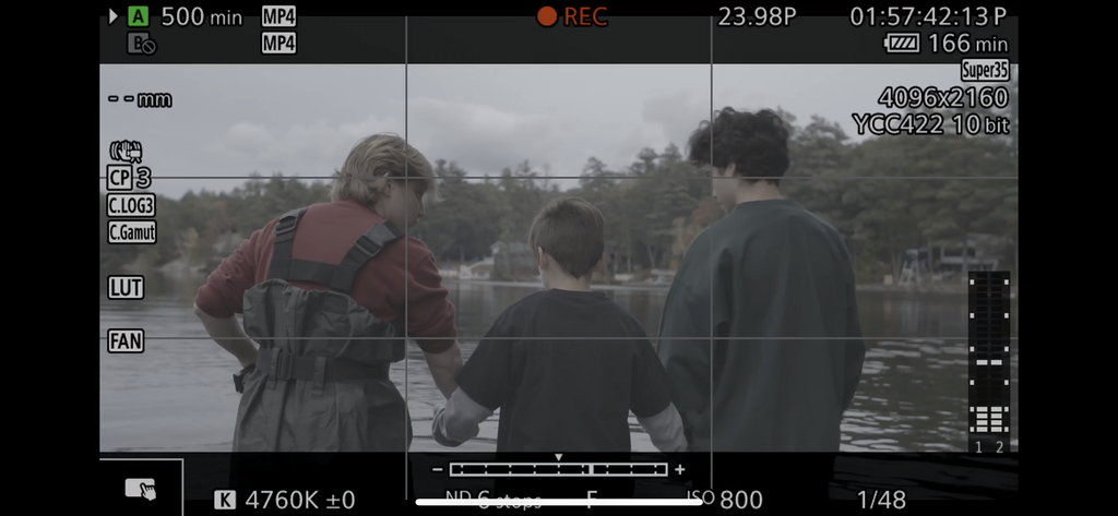 Viewfinder of camera on set. Actors stand facing away from the camera in the center of the frame.