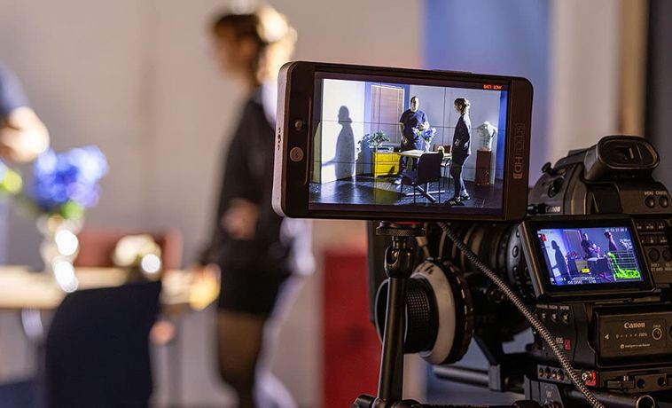 Camera viewfinder in foreground with two people standing in soft focus in the background.