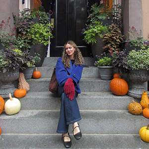 A photo of Olivia Fletcher sitting on stairs with pumpkins.