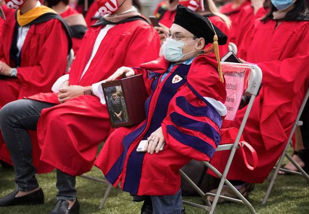 School of Law graduate Gaetano Mortillaro in his graduate cap and gown watches the 2021 BU Commencement ceremony for advanced degree students.