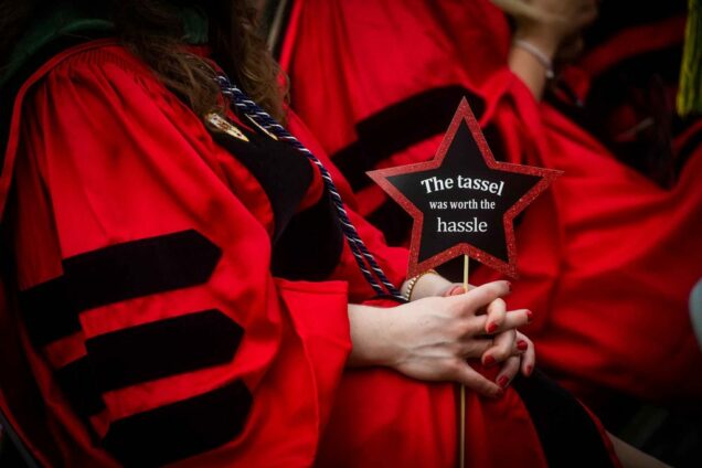 Detail photo of a graduate's star-shaped sign that says 'The tassel was worth the hassle.'