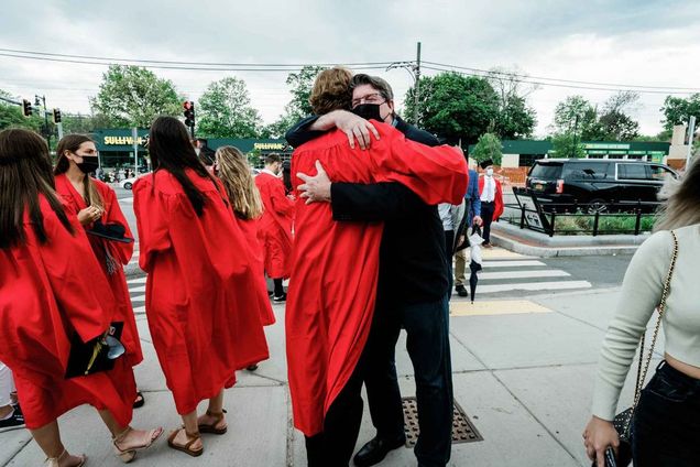 A graduating student hugs a family member on Commonwealth Ave. outside of the BU Commencement ceremony.