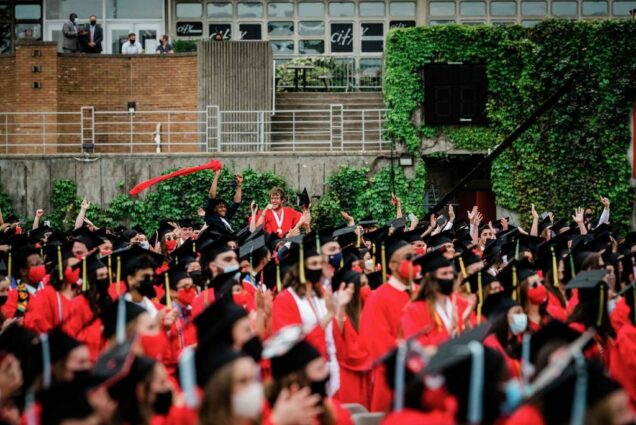 Two students at the back of a seating section celebrate and cheer during Boston University's 2021 Commencement for undergraduate degrees.