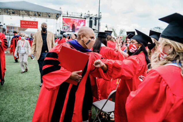 US Representative Ayanna Pressley gives a graduating BU student and elbow bump on Nickerson Field during BU's 2021 Commencment ceremony for undergraduates.