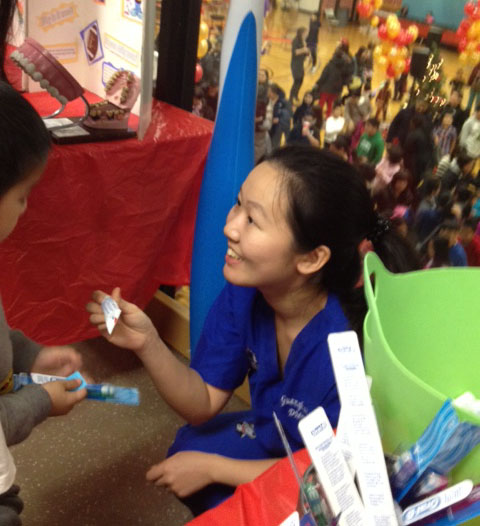 Guanghui Ling AS 16 gives toothpaste and a toothbrush to a young visitor at the Wang YMCA Holiday Party.