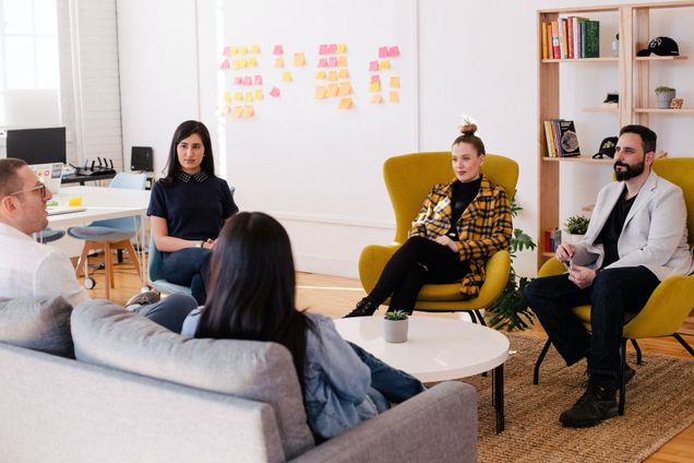 Group of five people sitting in an office setting