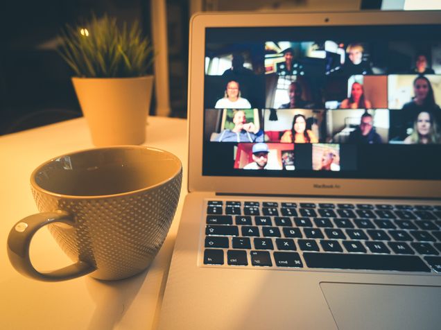 Laptop of zoom meeting next to a mug