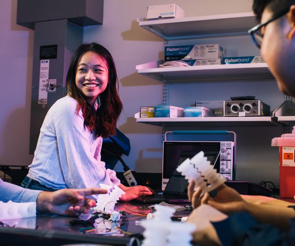 Female engineering student smiling as she works with other students in a lab setting