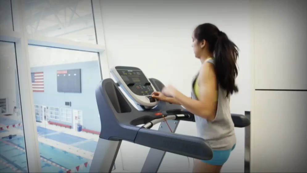 woman running on a treadmill and adjusting the speed