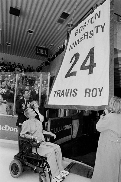 Travis Roy watches as a banner with his name and BU hockey jersey number are lifted to the rafters in Walter Brown Arena during a ceremony retiring his number in 1999