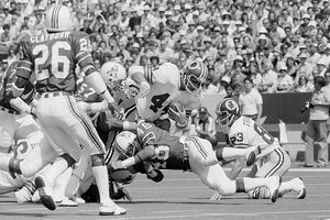 Washington Redskins' John Riggins busts through New England Patriots defensive player Tim Fox early in the first quarter at Foxboro, Mass., Sept. 3, 1978