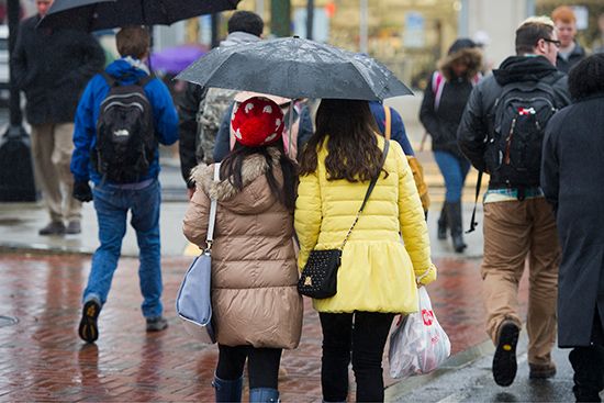 Two students under an umbrella in the rain