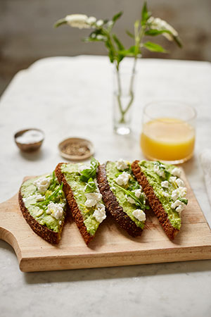 avocado toast topped with lemon zest, ricotta, and kale salt