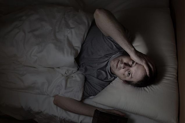 Man in bed with insomnia experiencing a lack of REM sleep