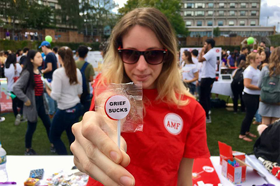 Allison Zuckerberg, President of the BU chapter of Actively Moving Forward holds a lollipop that says Grief Sucks