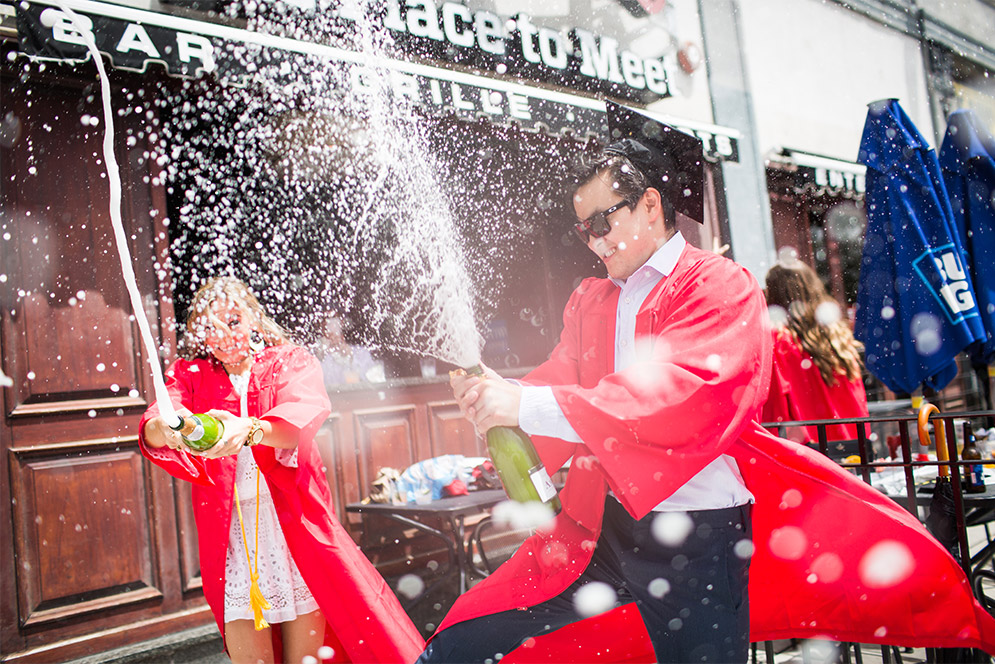 BU students spray champagne celebrating their graduation from the University