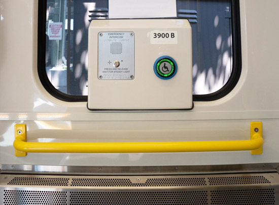 Bright yellow bars and an emergency button inside a new MBTA green line car.
